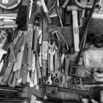 Ayudha Puja is collection of various tools like hammers, wrenches, knives, and pliers arranged on a wooden surface.