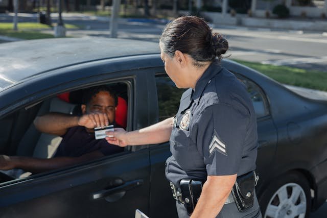 A police officer collects a driver's ID during a traffic stop.
