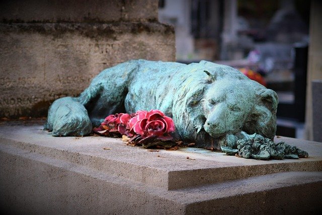 How Much Does It Cost to Cremate a Dog: Bronze statue of a dog, likely part of a memorial or cemetery monument.